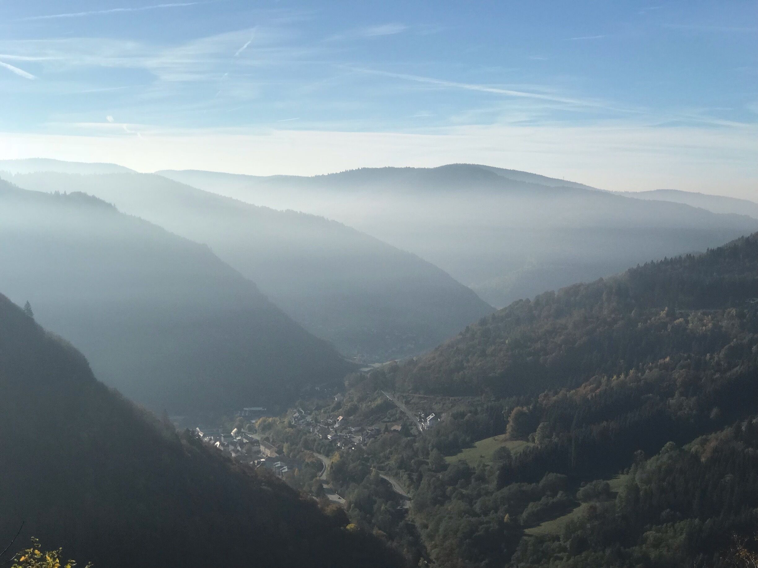 A valley with a town nestled among rolling hills and covered in mist.