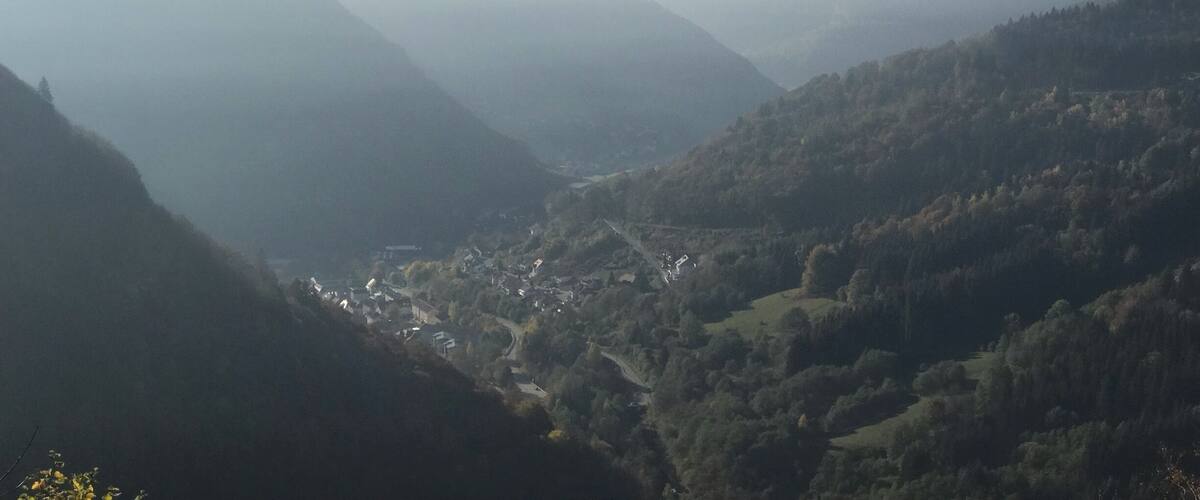 A valley with a town nestled among rolling hills and covered in mist.