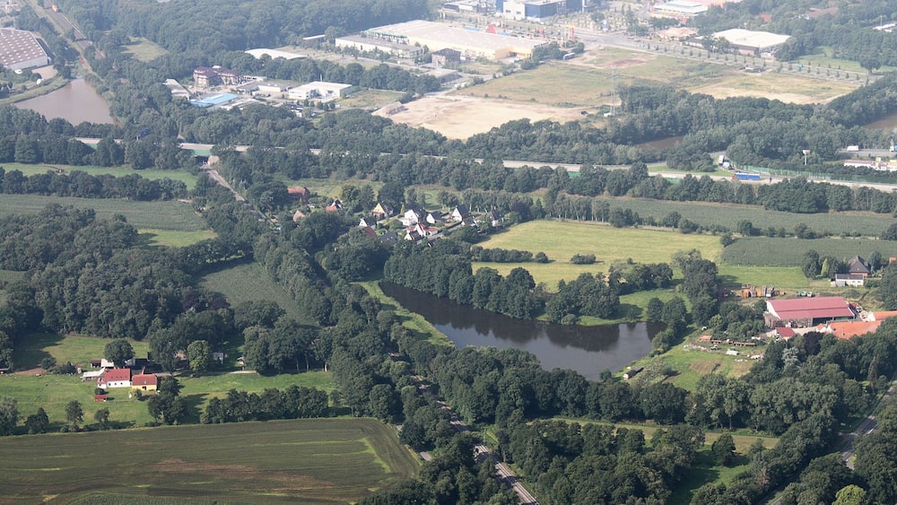 An aerial view of a rural landscape with fields, a lake, and scattered buildings.