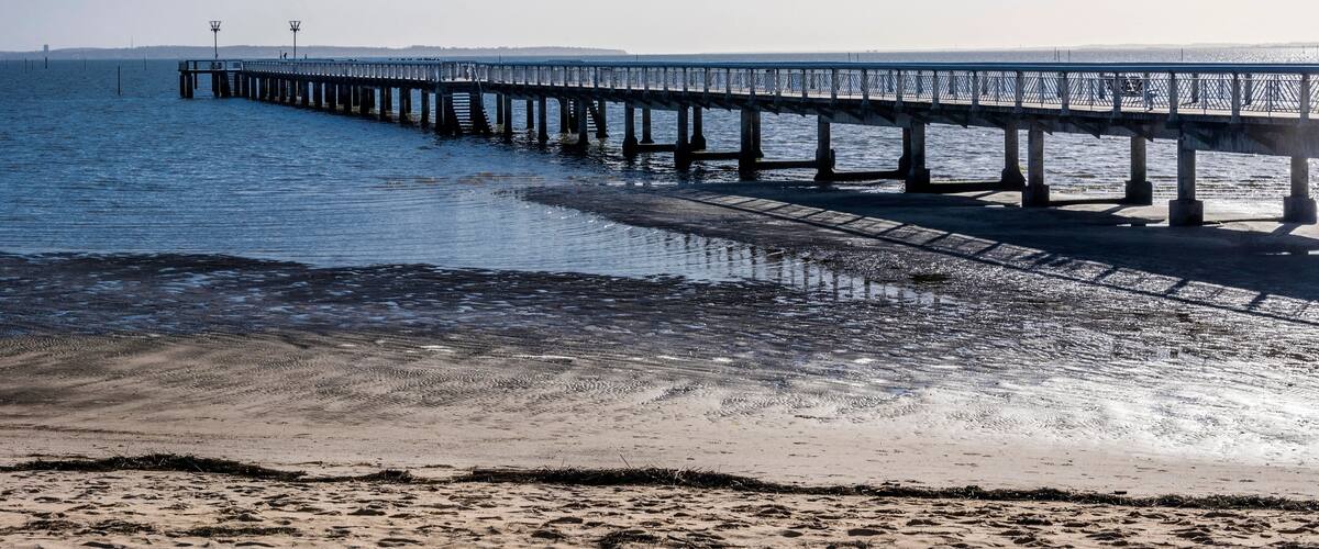 A pier extending into calm waters with a clear sky.