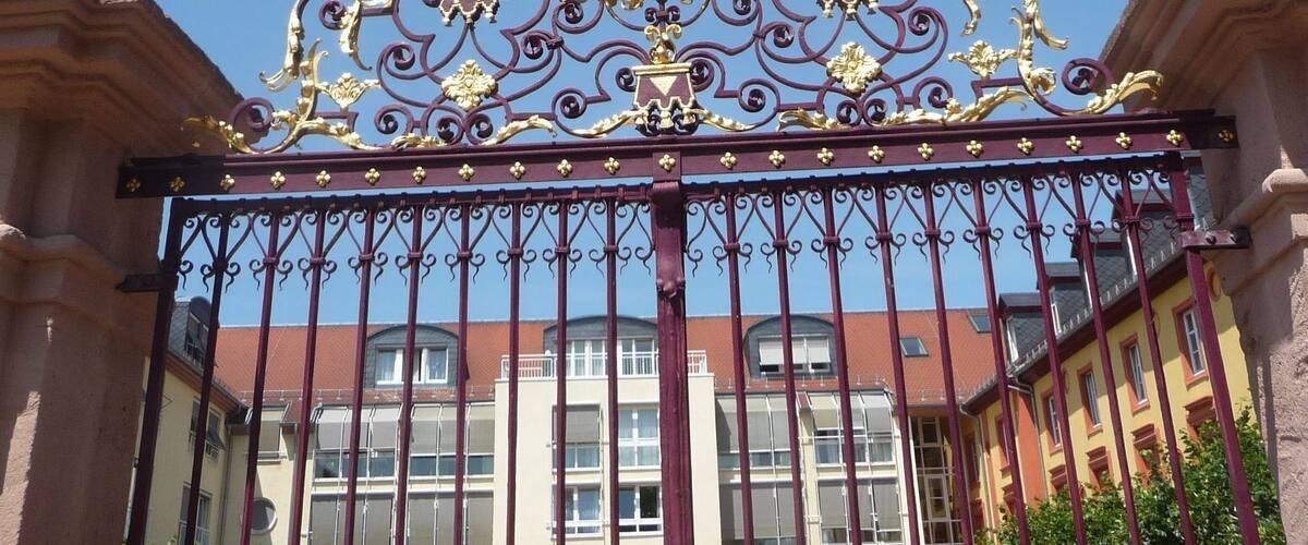 A wrought iron gate with ornate designs and two stone pedestals.
