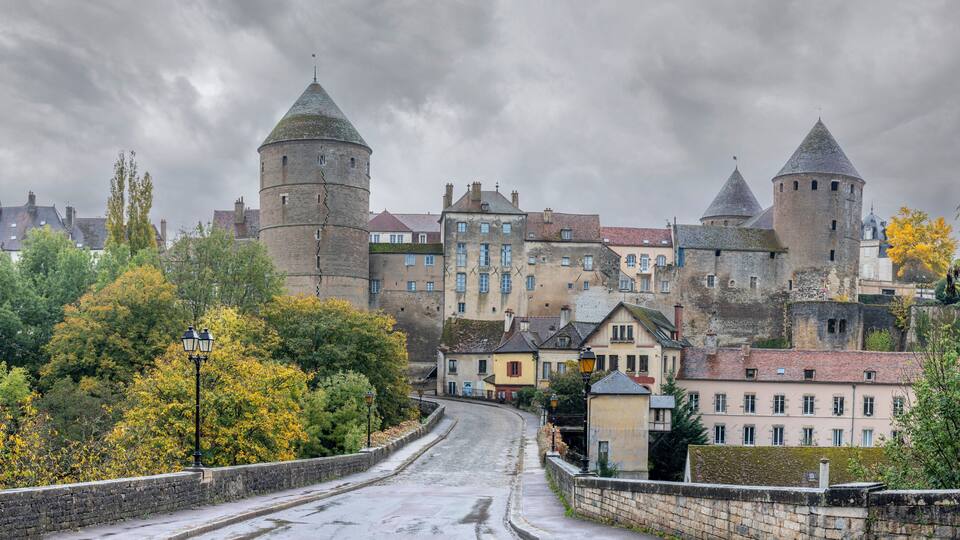A historic town with medieval towers, cobblestone streets, and autumn foliage.