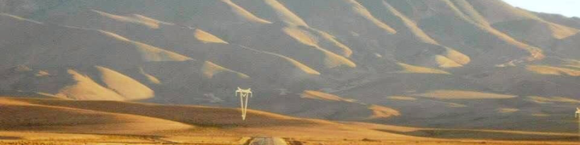 Una carretera que se dirige hacia una cadena montañosa bajo un cielo despejado.