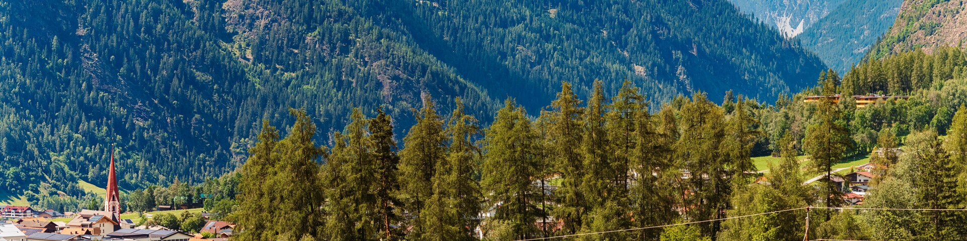 A mountainous landscape with dense forests, a church, and residential buildings.