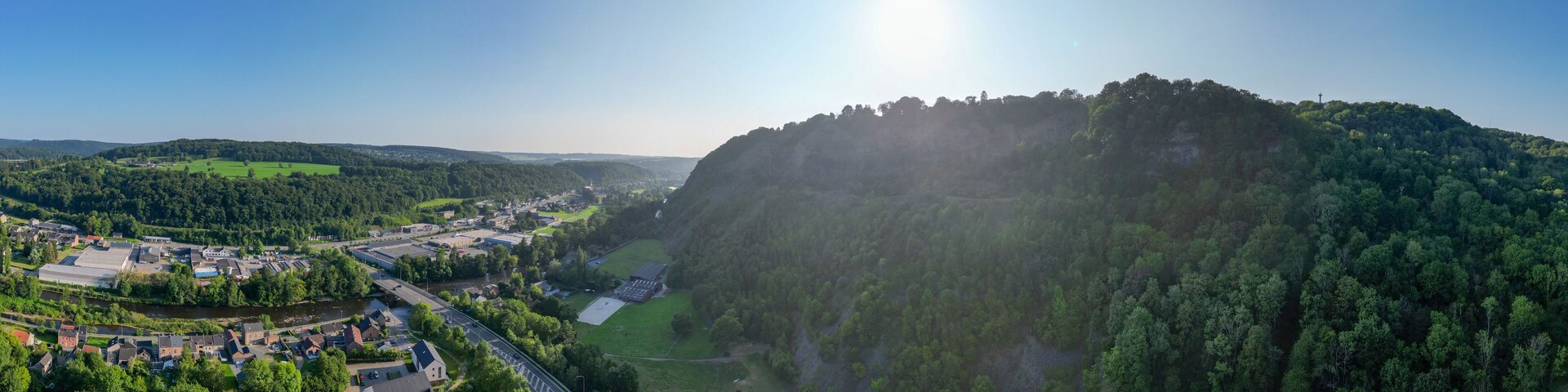 A river valley with a bridge, a town, and a forested hill.