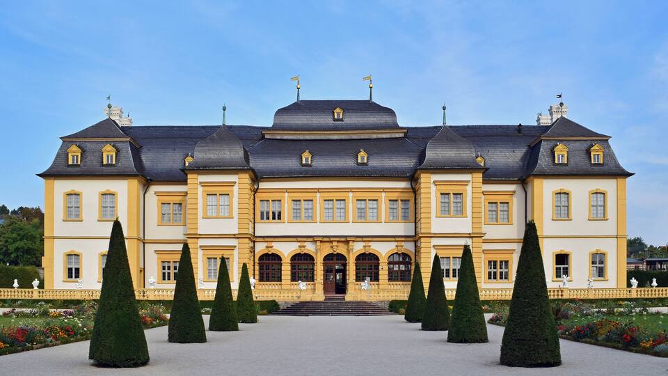 A large, yellow and white building with a symmetrical facade, multiple windows, and a central entrance.