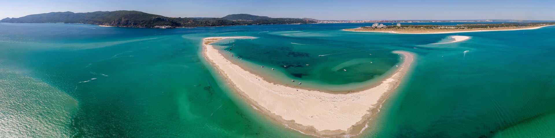 Aerial drone panoramic view of beautiful sandy beaches stretching along the coastline of Troia, Portugal, as turquoise waters glisten under the bright sun