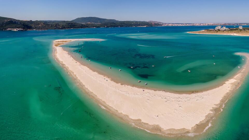 A coastal landscape with a prominent bay, clear turquoise waters, and a sandy beach.