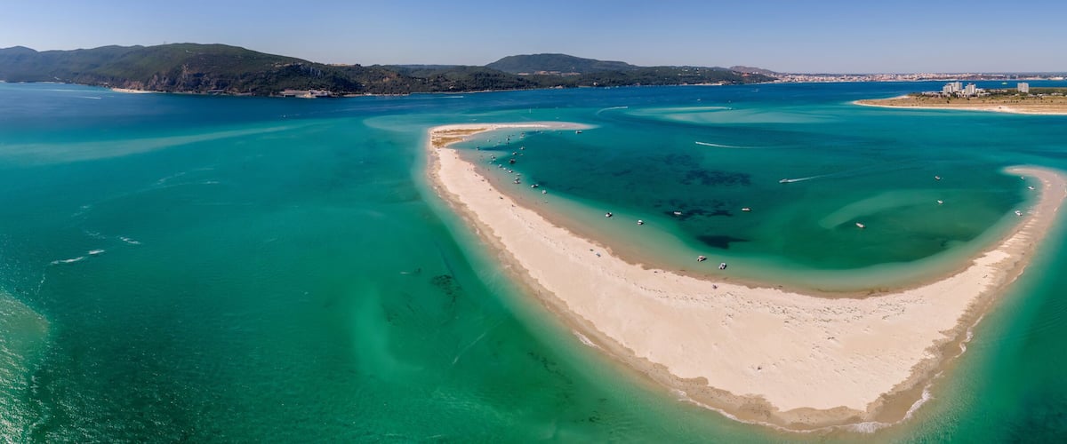 A coastal landscape with a prominent bay, clear turquoise waters, and a sandy beach.