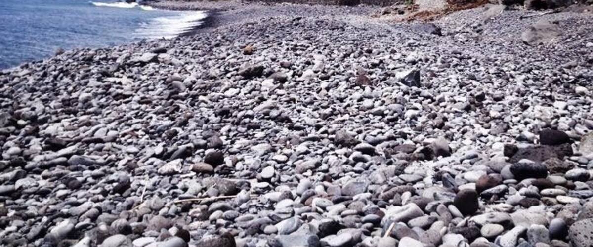A rocky beach with a building on a cliff.