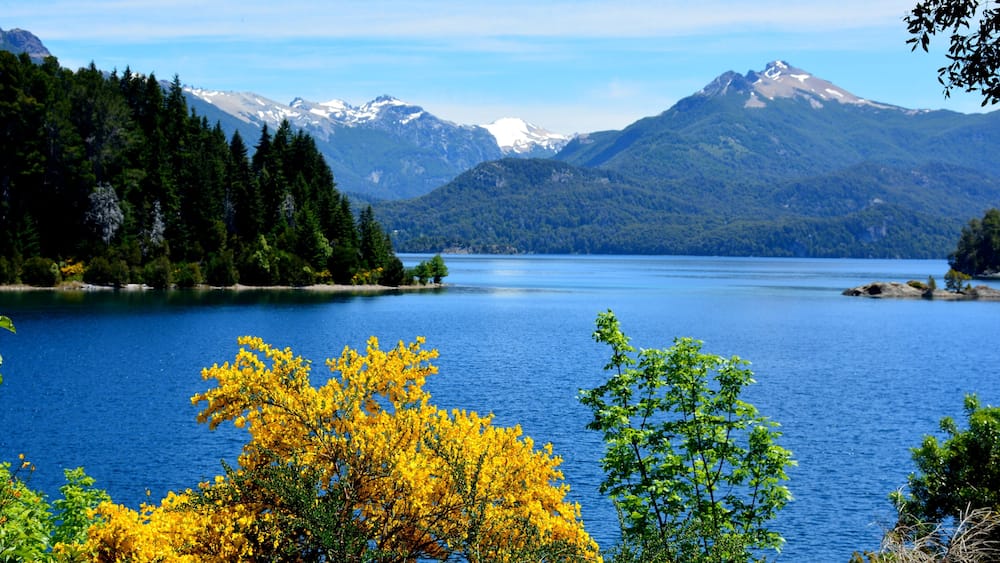 Ein See, umgeben von Bergen und Bäumen mit gelbem Herbstlaub.