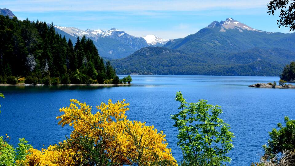 A lake surrounded by mountains and trees with yellow foliage.