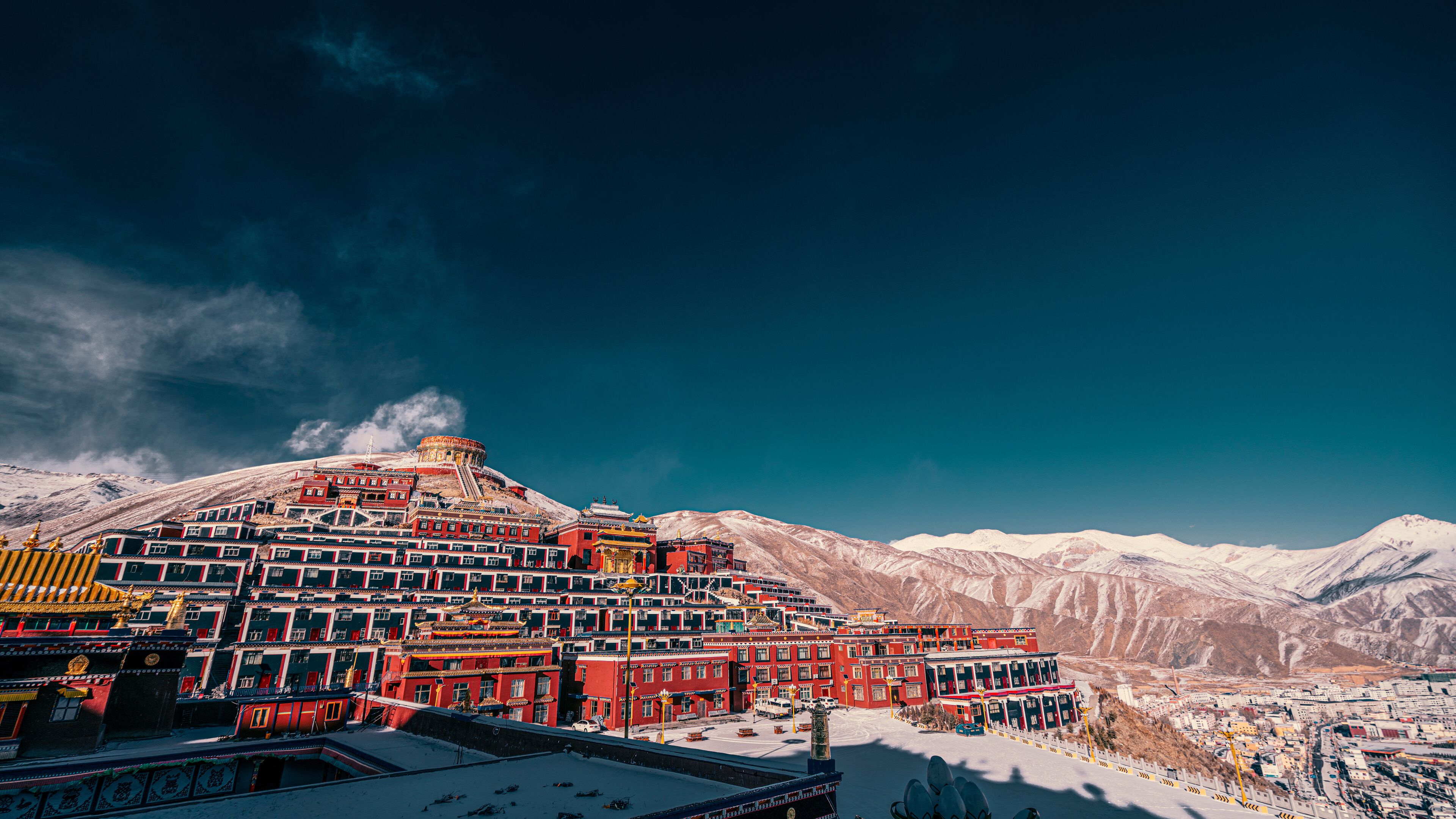 A snow-covered mountain range with a traditional red-roofed building complex.