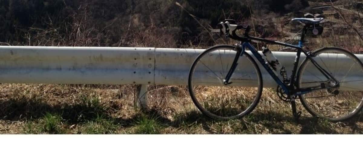 A bicycle parked by a guardrail with a snow-capped mountain in the background.