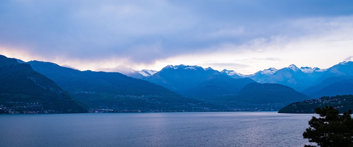 A mountain range with a lake in the foreground and snow-capped peaks in the background.