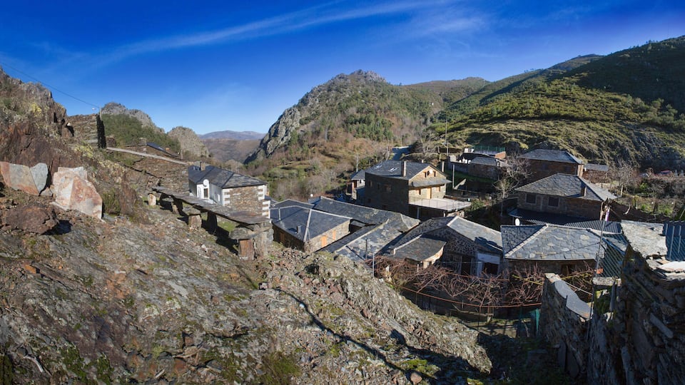 A mountainous village with stone houses and a stone bridge.