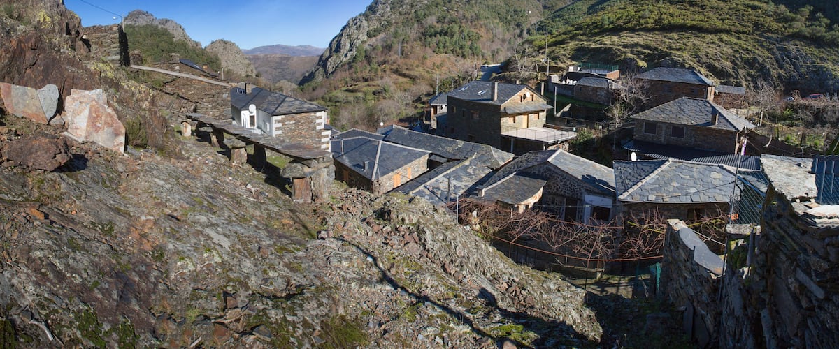 A mountainous village with stone houses and a stone bridge.