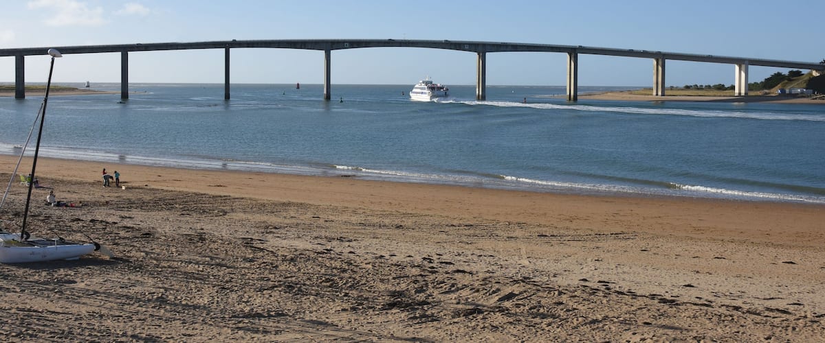 A beach with a large bridge over the water.