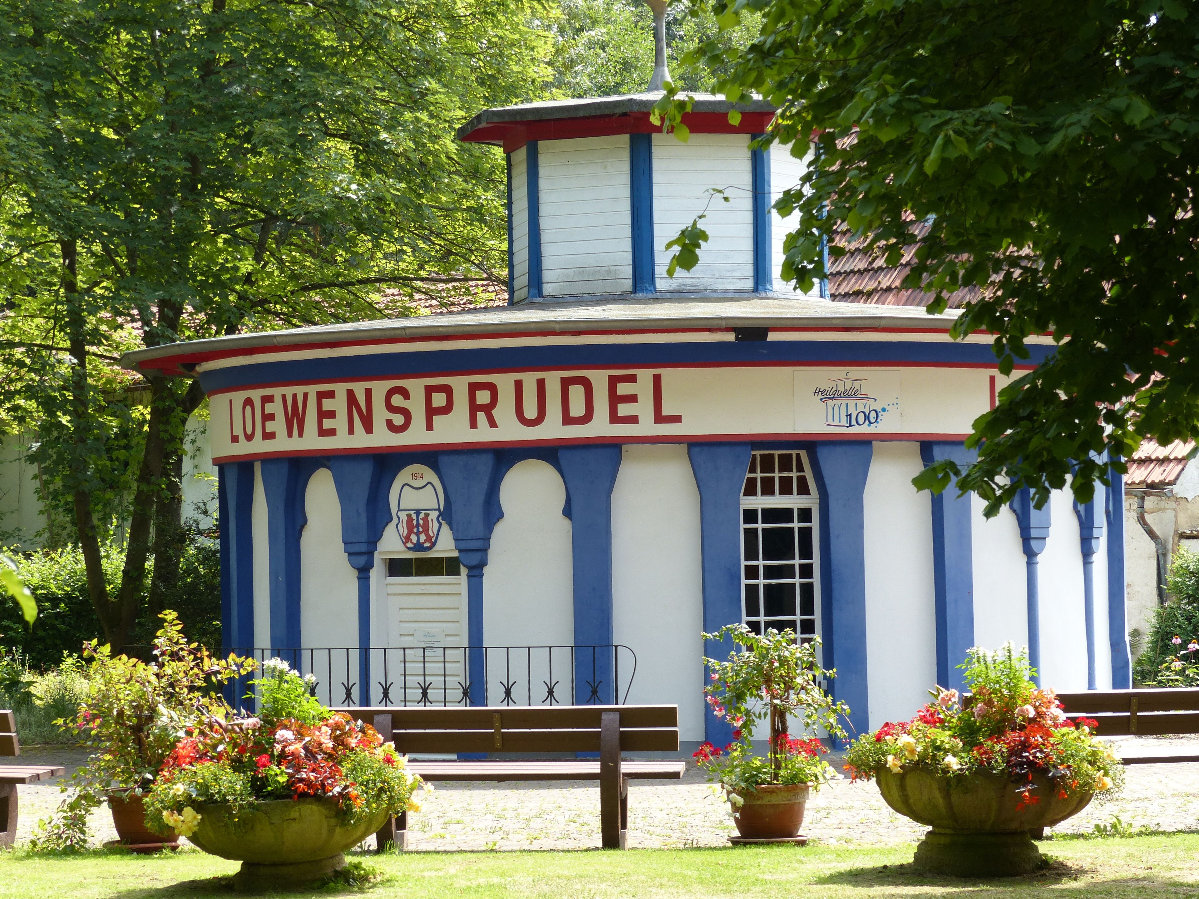 A building with the sign 'LOEWENSPRUDEL' and a year '1914' on it.