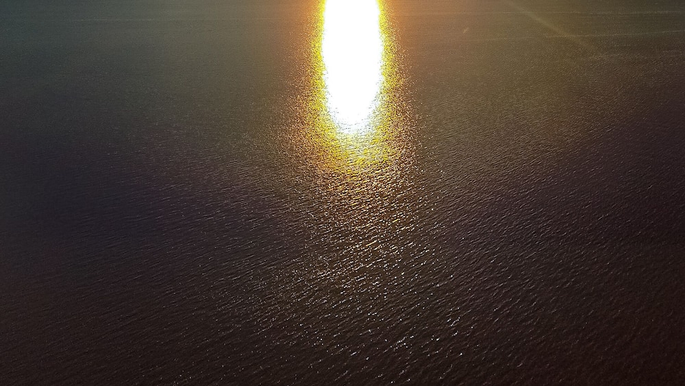 Un coucher de soleil sur une étendue d’eau calme, sous un ciel dégagé.