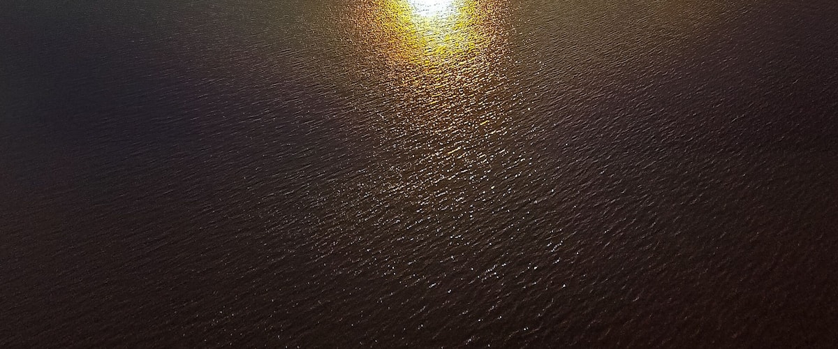 A sunset over a calm body of water with a clear sky.