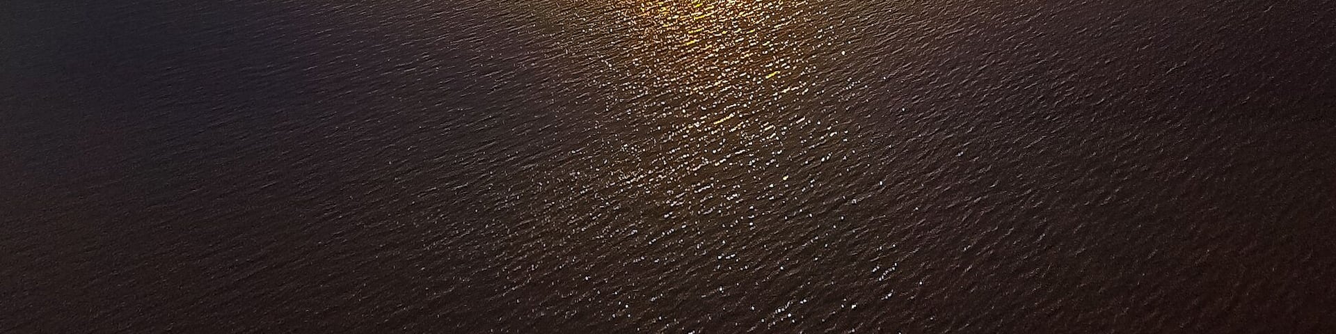 A sunset over a calm body of water with a clear sky.