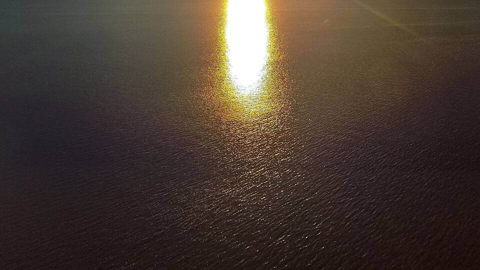 A sunset over a calm body of water with a clear sky.