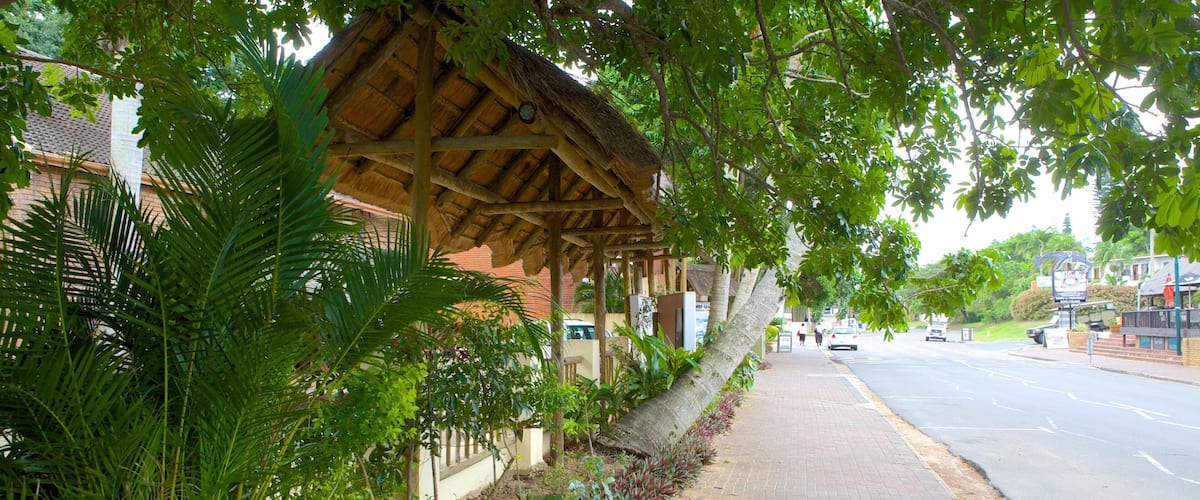 A covered walkway with lush greenery and a street in the background.