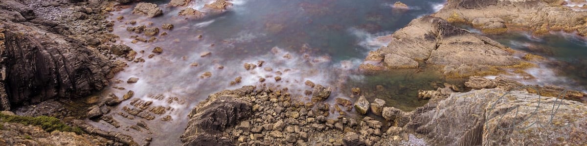 A rugged coastline with rocky outcrops and a clear view of the ocean.