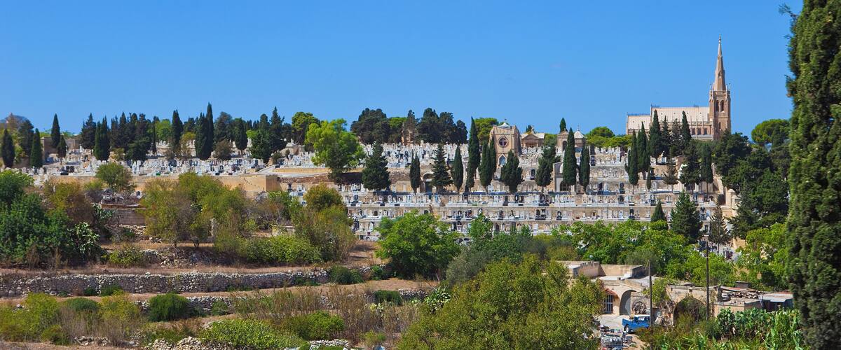 A cemetery with tombstones and a church with a tall spire.