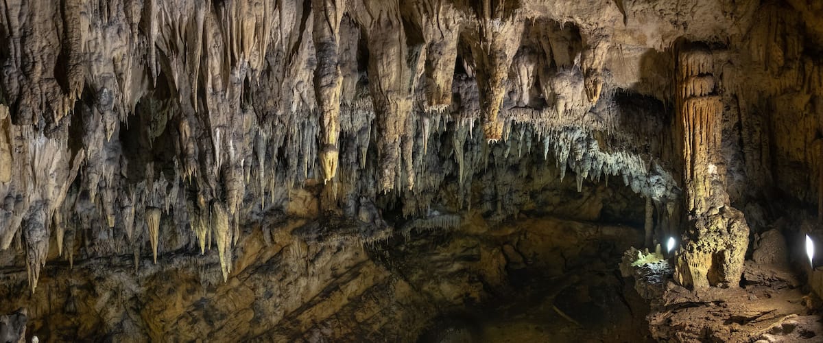 A cave with stalactites hanging from the ceiling and stalagmites rising from the ground.