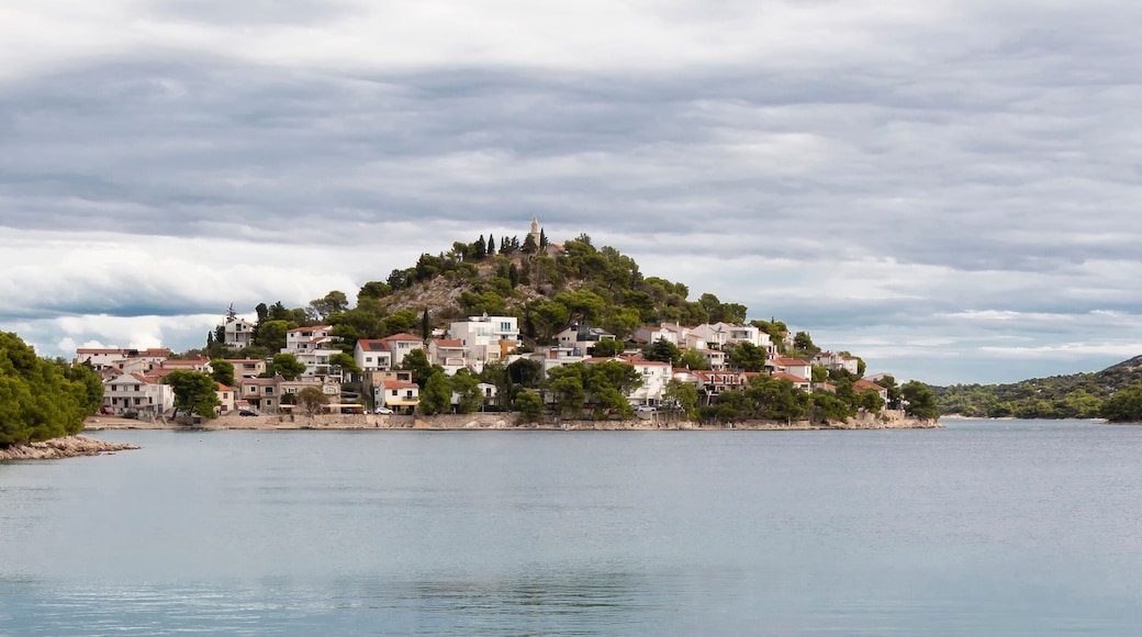 Rocky beach and hill with St Nicholas church in Tribunj, Croatia