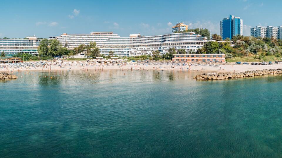 A coastal resort with a beach, a marina, and high-rise buildings in the background.