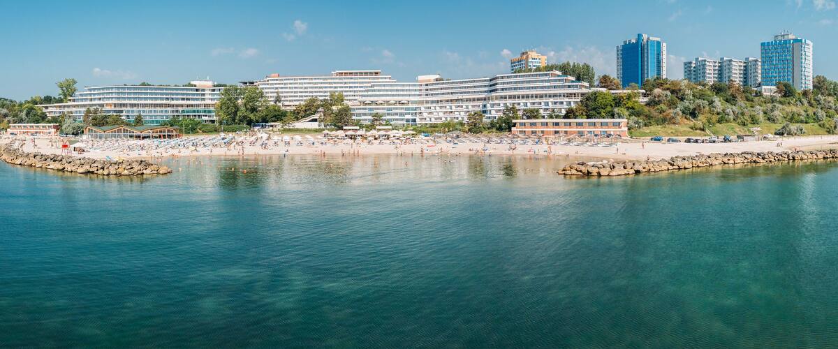 A coastal resort with a beach, a marina, and high-rise buildings in the background.