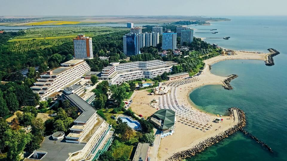 An aerial view of a coastal resort with high-rise buildings, a beach, and a rocky shoreline.
