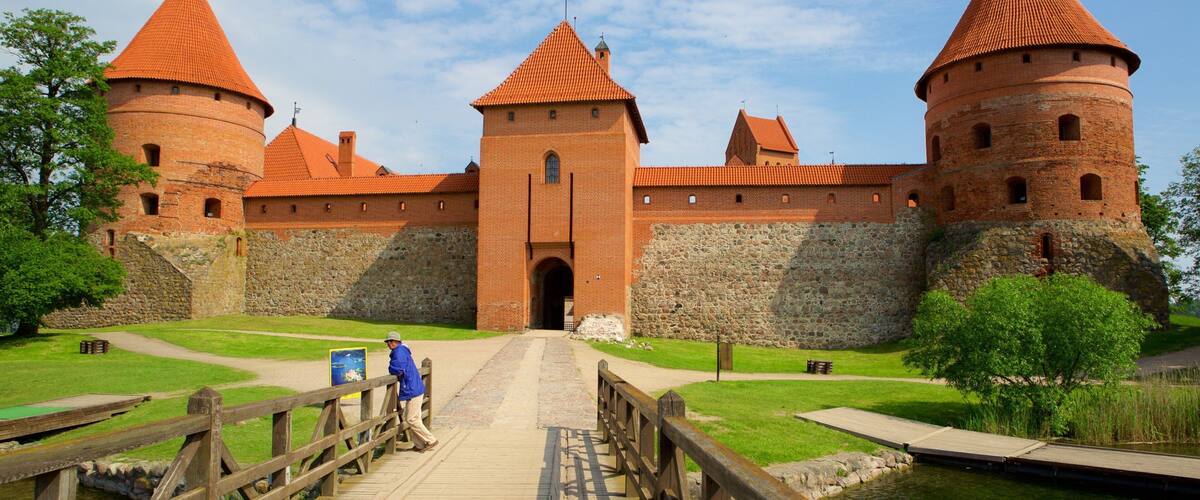 A historic brick castle with red-tiled roofs and a wooden bridge leading to the entrance.