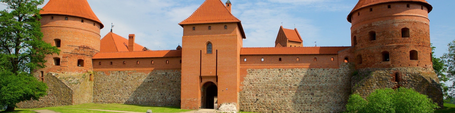 A historic brick castle with red-tiled roofs and a wooden bridge leading to the entrance.