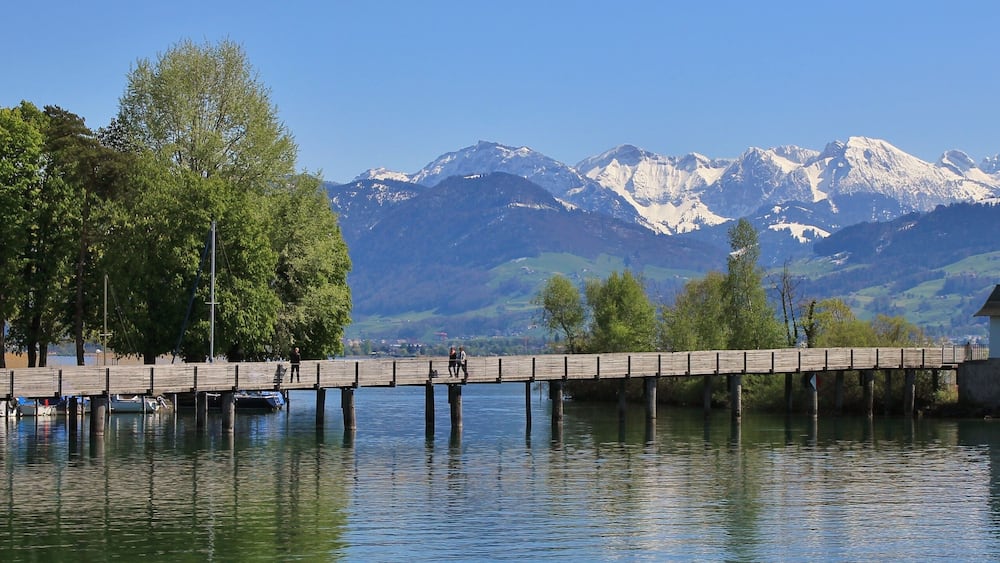 Timber gangplank in Rapperswil. Lake Zurichsee and snow capped mountains. Springtime.