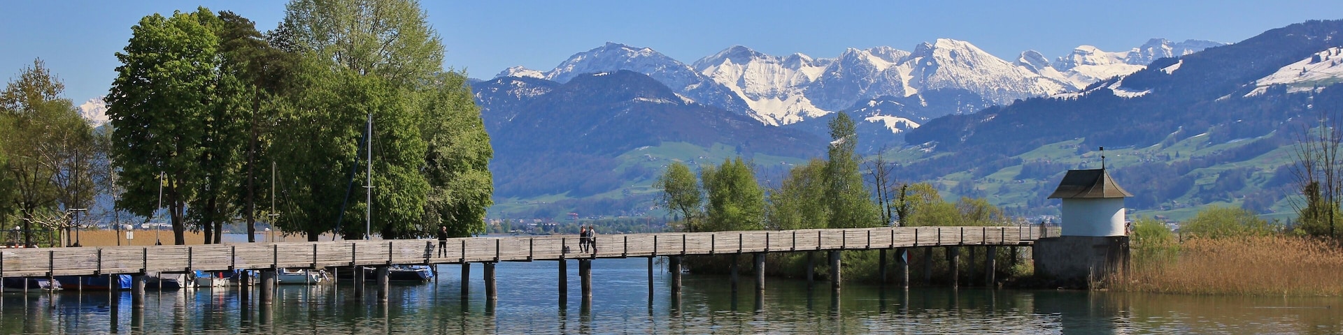 Timber gangplank in Rapperswil. Lake Zurichsee and snow capped mountains. Springtime.