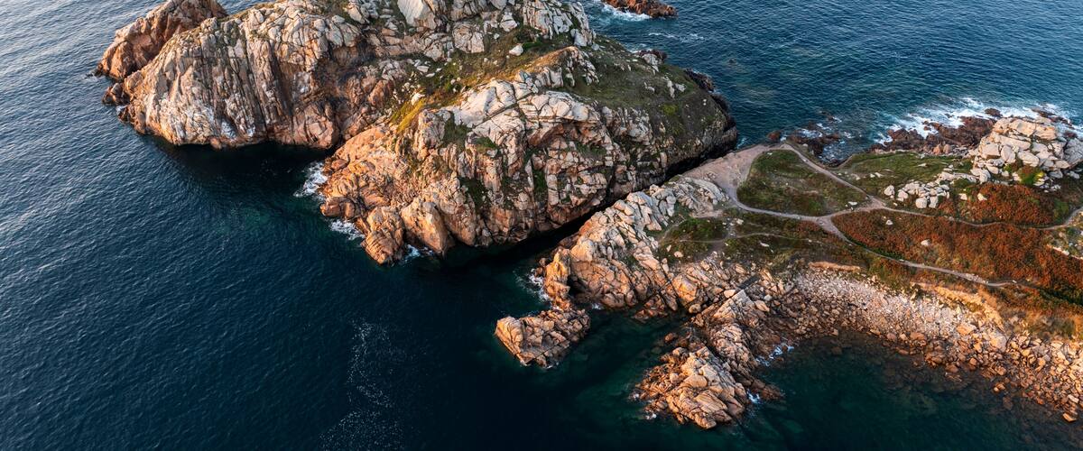 A rugged coastline with rocky outcrops and clear blue waters.