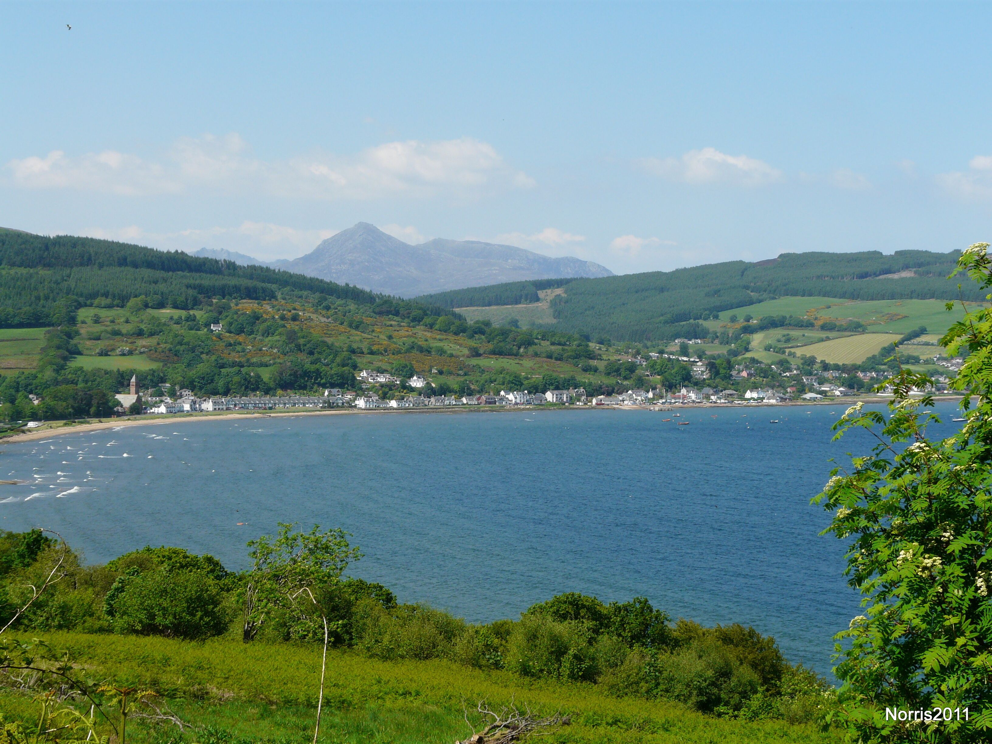 A coastal town with a church, houses, and boats on the water.