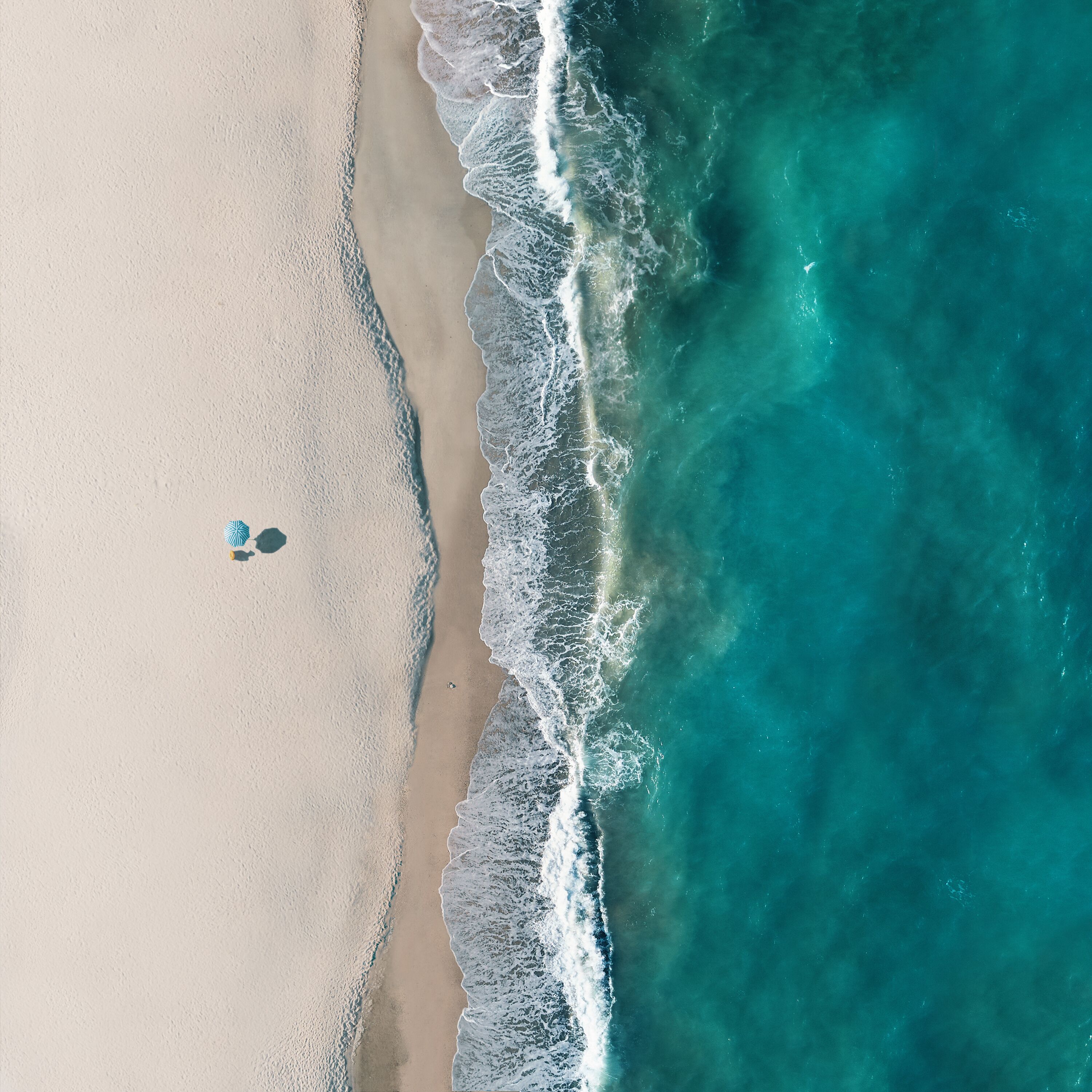 Aerial view of a lonely beach umbrella along the sea shore, Sant'Andrea Apostolo dello Ionio, Calabria, Italy.