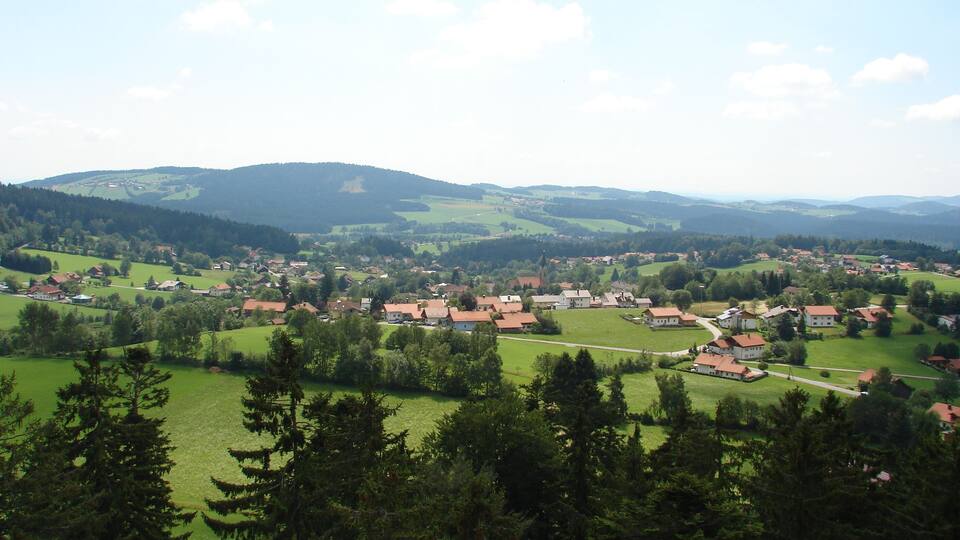 A village nestled in a valley with green fields and houses.
