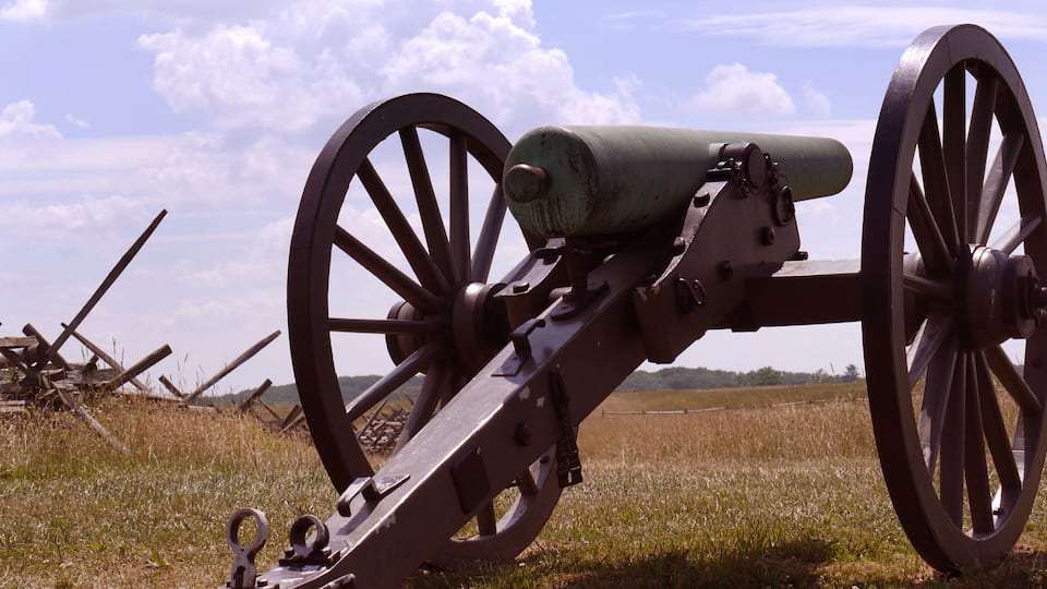 A cannon with large wheels in a grassy field.
