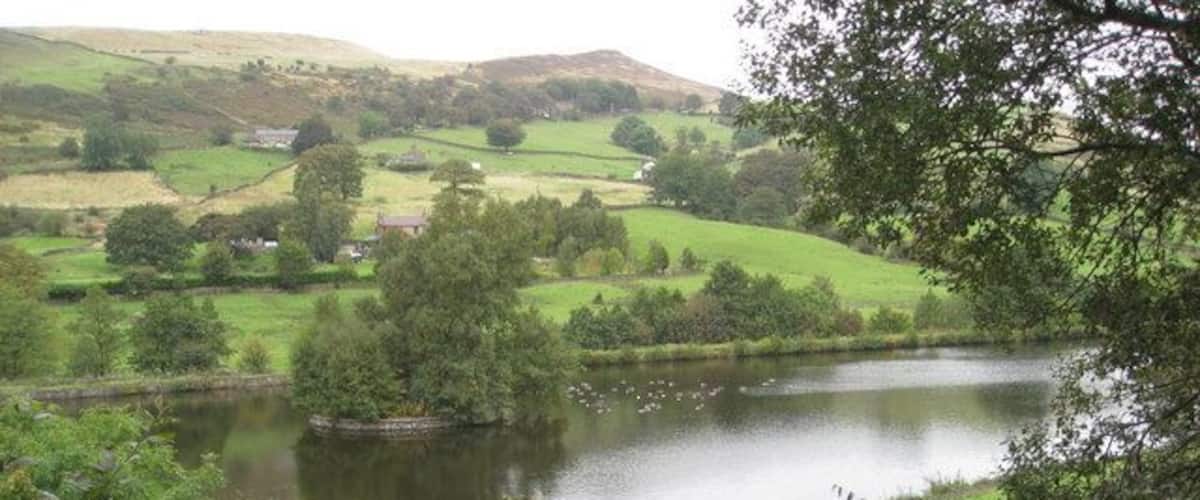 A lake surrounded by lush greenery and rolling hills.