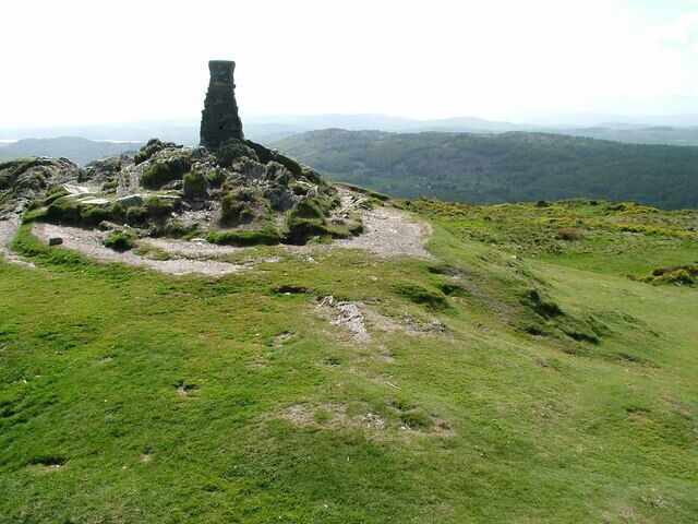 A grassy hill with a stone structure in the center.
