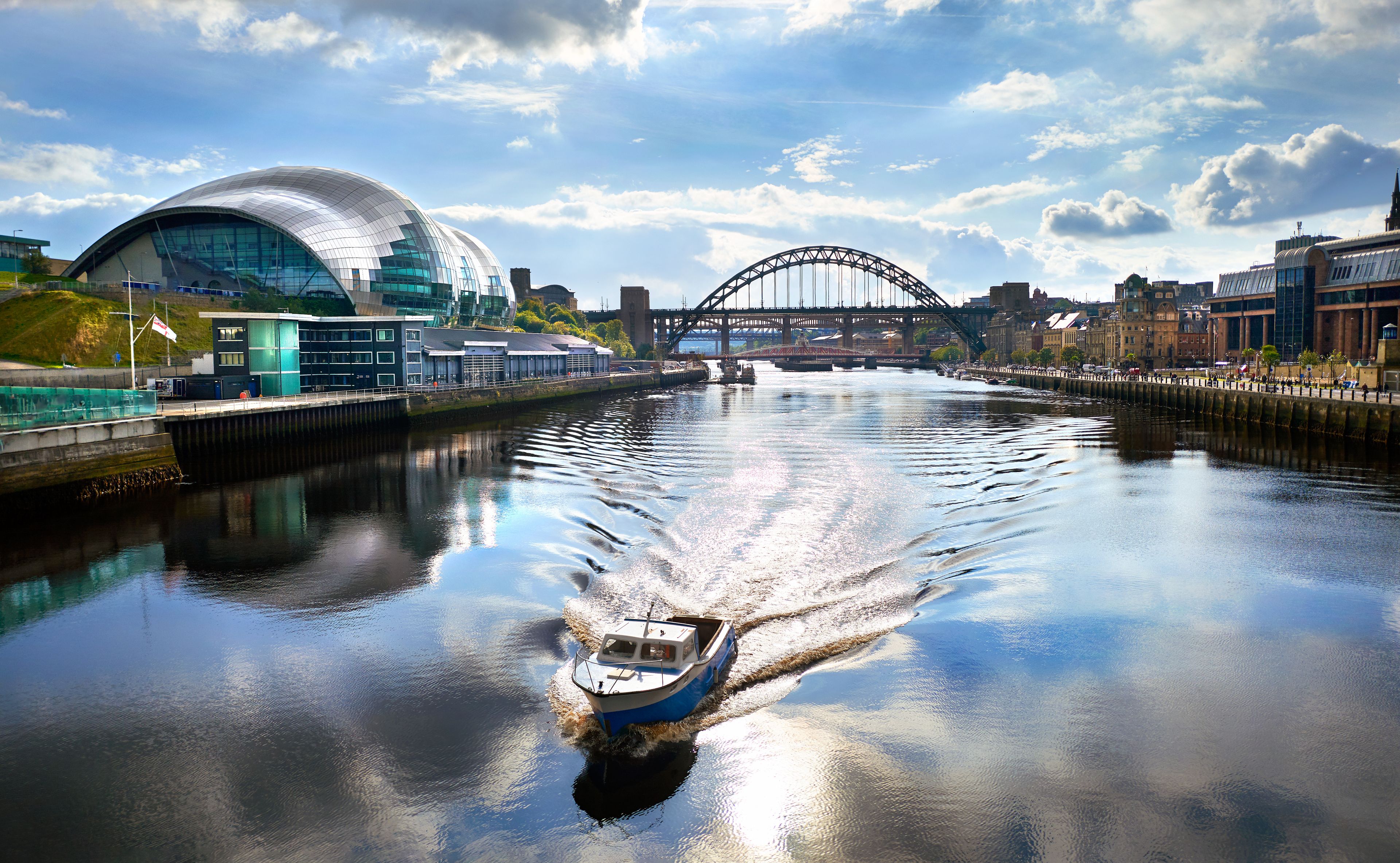 A river with a boat, a modern building, and a bridge.