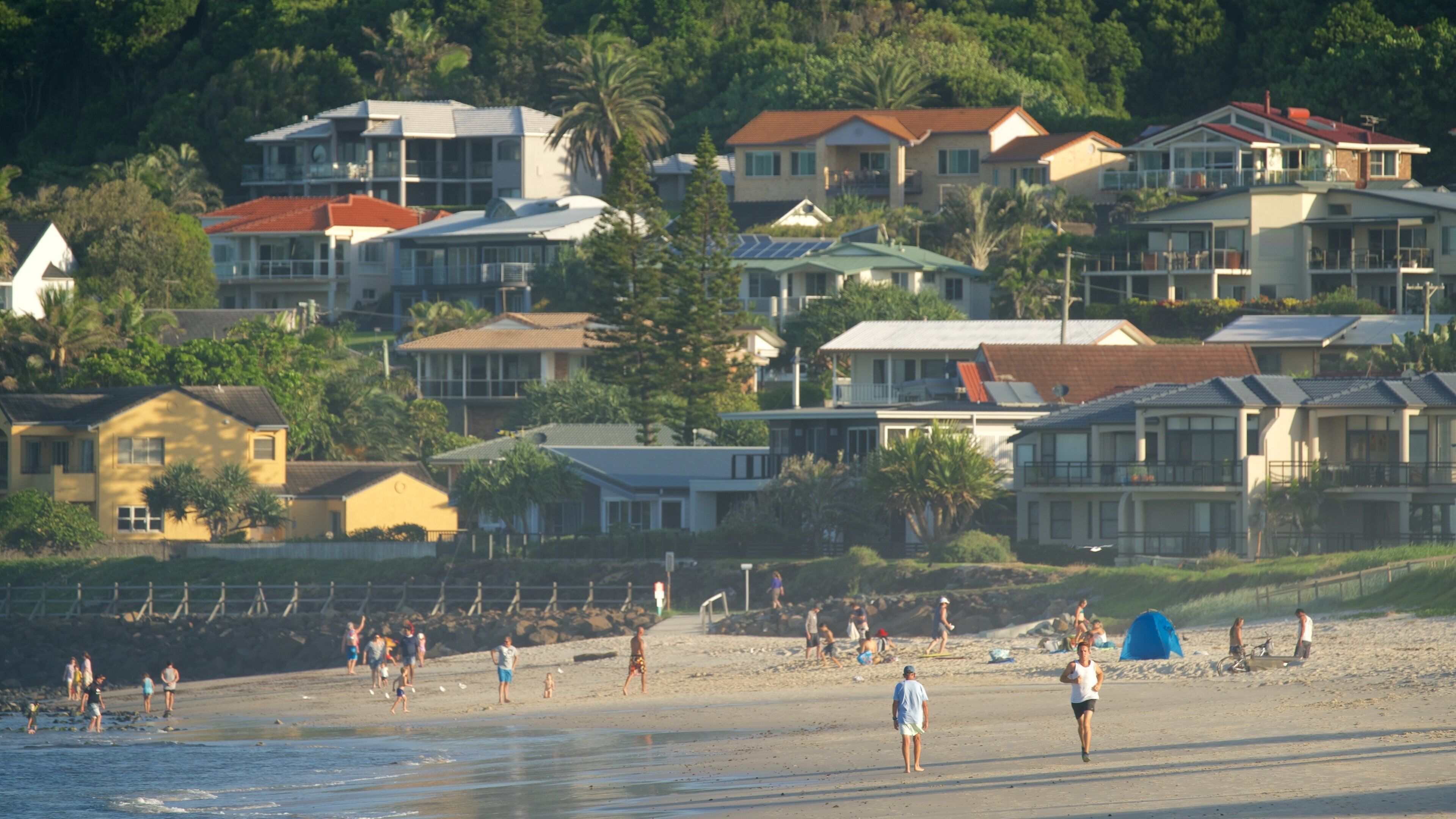 Una playa con gente, casas y palmeras.