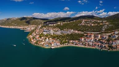 A coastal town with a marina, dense buildings, and mountainous terrain in the background.