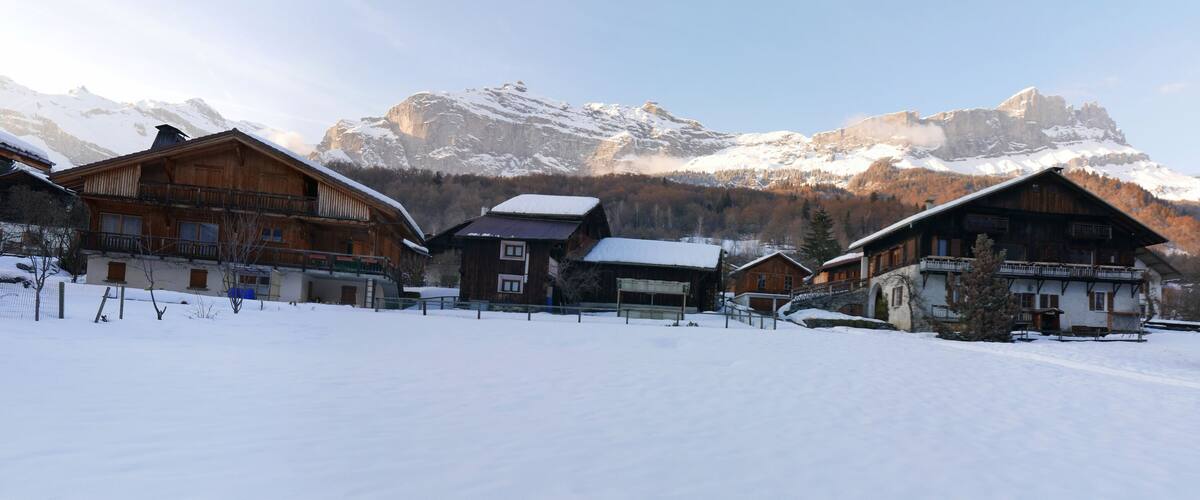 A snow-covered village with wooden houses and mountains in the background.